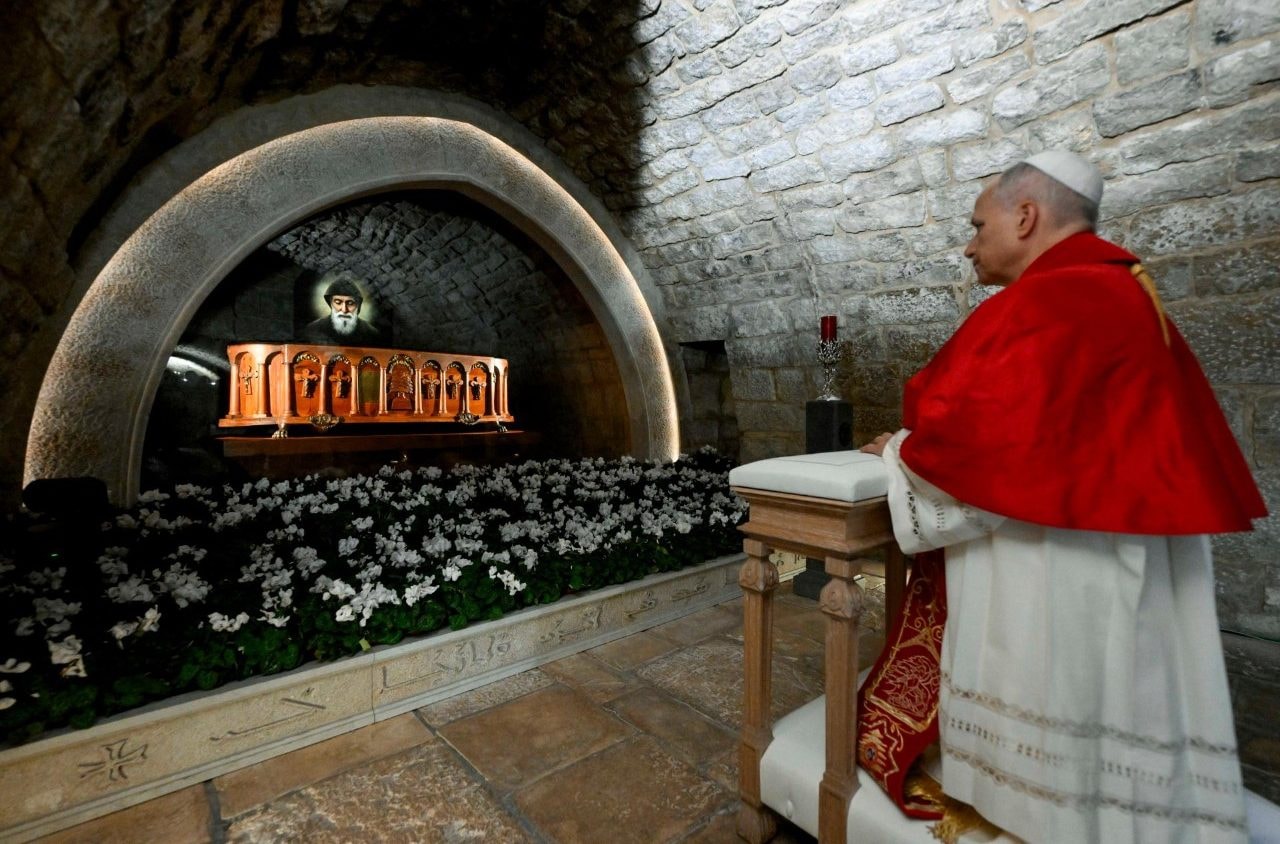 Pope Leo XIV kneeling in prayer at the tomb of Saint Sharbel
